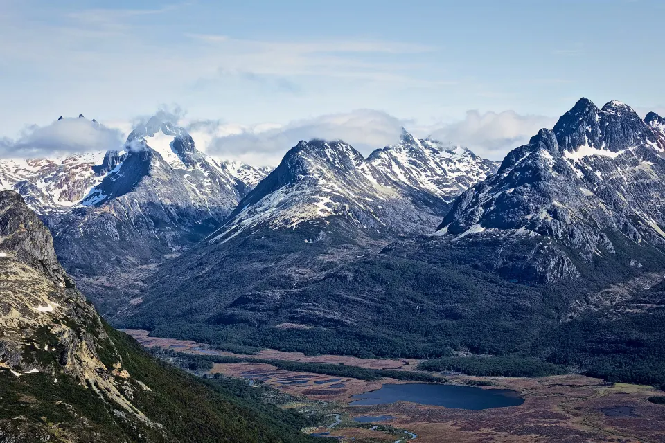 Vista aérea de las montañas nevadas y los turbales del Valle Carbajal, con una laguna, cerca de Ushuaia