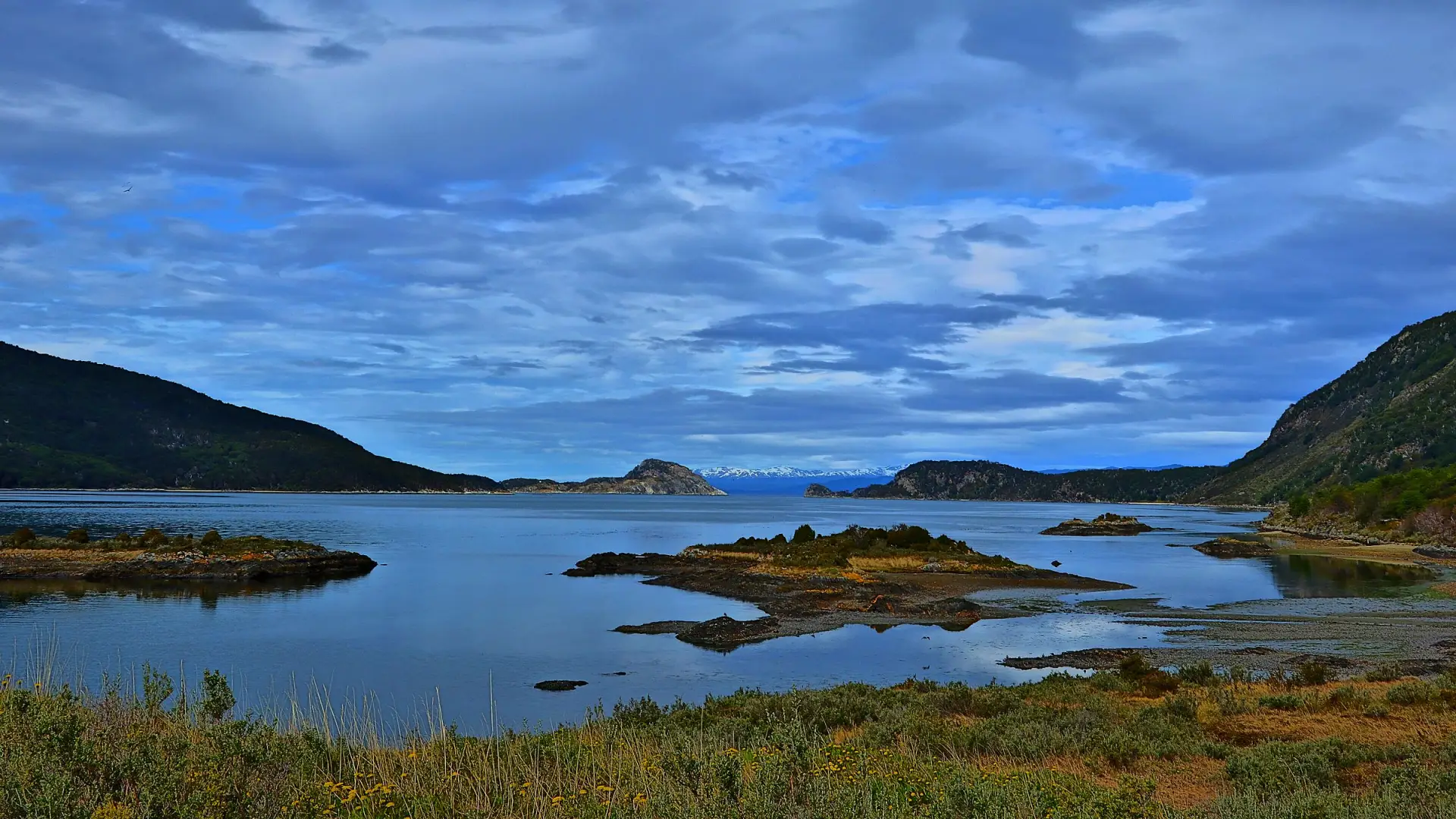 La Bahía Lapataia, en el Parque Nacional Tierra del Fuego: islotes, cerros con bosque y un cielo con nubes
