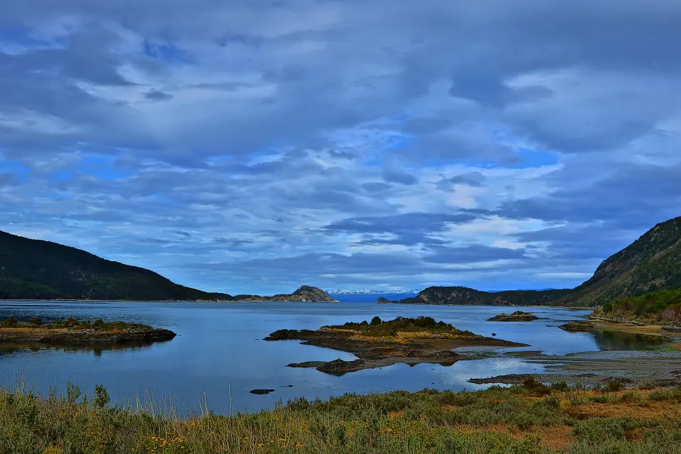 La Bahía Lapataia, en el Parque Nacional Tierra del Fuego: islotes, cerros con bosque y un cielo con nubes